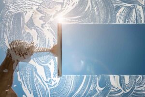 Window cleaner using a squeegee to wash a window with clear blue sky