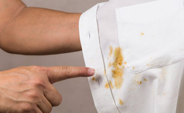 person pointing to spilled curry stain on white shirt